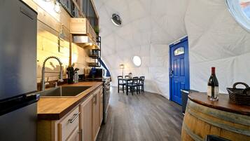 A compact kitchen with wooden cabinets, a sink, and a dining area with a table and chairs.