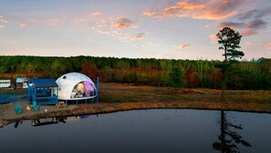 Una tenda a forma di cupola con esterno blu e interno bianco, adiacente a uno specchio d'acqua.