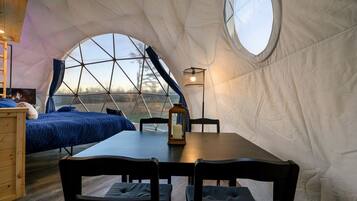 A dome-shaped tent with a bed, a table, and chairs.