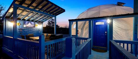 A covered outdoor area with a blue-roofed structure, a blue door, and a wooden deck.