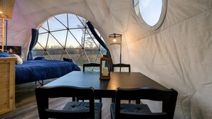 A dome-shaped tent with a bed, a table, and chairs.