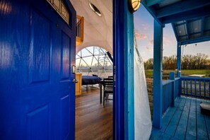 A geodesic dome room with a bed, a table, and a chair.