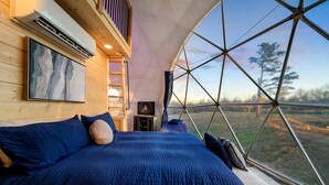 A tent-style room with a bed, a painting, and a television.
