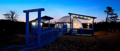 Una estructura abovedada con una entrada azul que dice 'INCREED-DOME' y un área de asientos cubierta con luces.