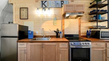 A kitchen with wooden cabinets, a stainless steel refrigerator, a sink, a stove, a microwave, and a coffee maker.