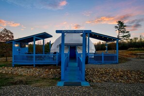 Eine blaue Struktur mit der Aufschrift 'INCREDI-DOME', einem überdachten Eingang und einer kleinen Sitzgelegenheit.