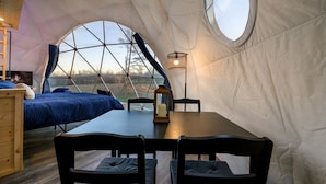 Una tenda a forma di cupola con un letto, un tavolo e delle sedie.