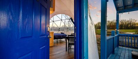 A geodesic dome room with a bed, a table, and a chair.
