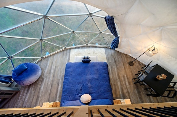 A geodesic dome interior with a bed, seating area, and a table.