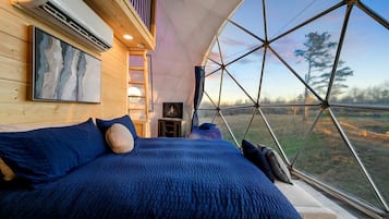 A tent-style room with a bed, a painting, and a television.