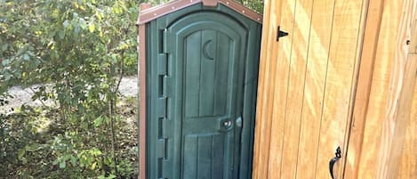 Una puerta de madera con un diseño de luna creciente, un picaporte metálico y un marco de madera.