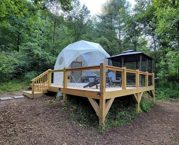 A wooden deck with a covered seating area and a gazebo.