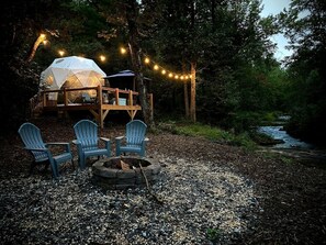 A tented accommodation with a deck, outdoor seating, and a fire pit.