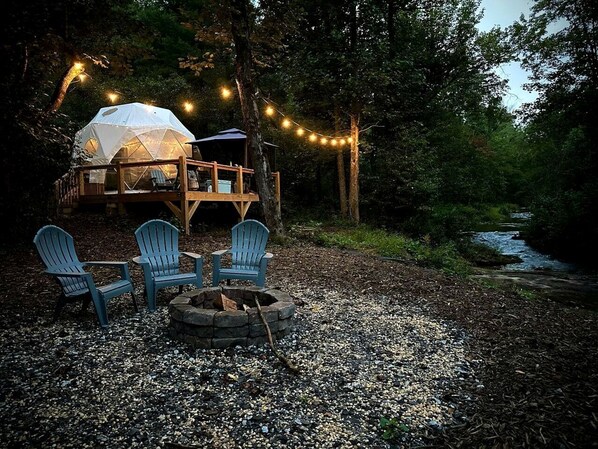 A tented accommodation with a deck, outdoor seating, and a fire pit.
