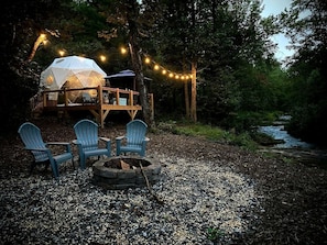 A tented accommodation with a deck, outdoor seating, and a fire pit.