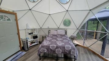 A room with a bed, a shelf with items, a door, and a window.