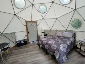 A room with a bed, a desk, a chair, and a storage box.