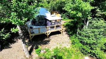 A treehouse with a dome-shaped roof, wooden deck, and a small table.