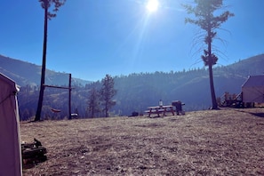A campsite with tents, a picnic table, and a clear view of a forested mountain range.