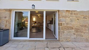 A building with a stone facade, a glass door entrance, and a visible interior with a dining area and kitchen. - Connect with yourself in a space of peace and tranquility. (Arbo)