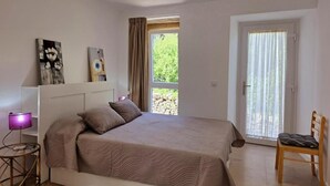 A bedroom with a bed, a chair, a desk with a lamp, and two paintings on the wall. - Connect with yourself in a space of peace and tranquility. (Arbo)