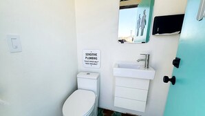 Un baño pequeño con inodoro, lavamanos y un letrero que indica fontanería delicada.