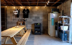 A kitchen with a wooden table, a refrigerator, and shelves with various items.