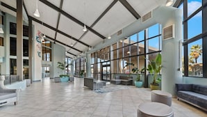 Eine geräumige Lobby mit hoher Decke, großen Fenstern und modernen Sitzbereichen.