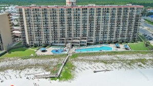 Ein Hochhaus-Hotel mit mehreren Balkonen, einem Schwimmbad und einer Strandanlage.