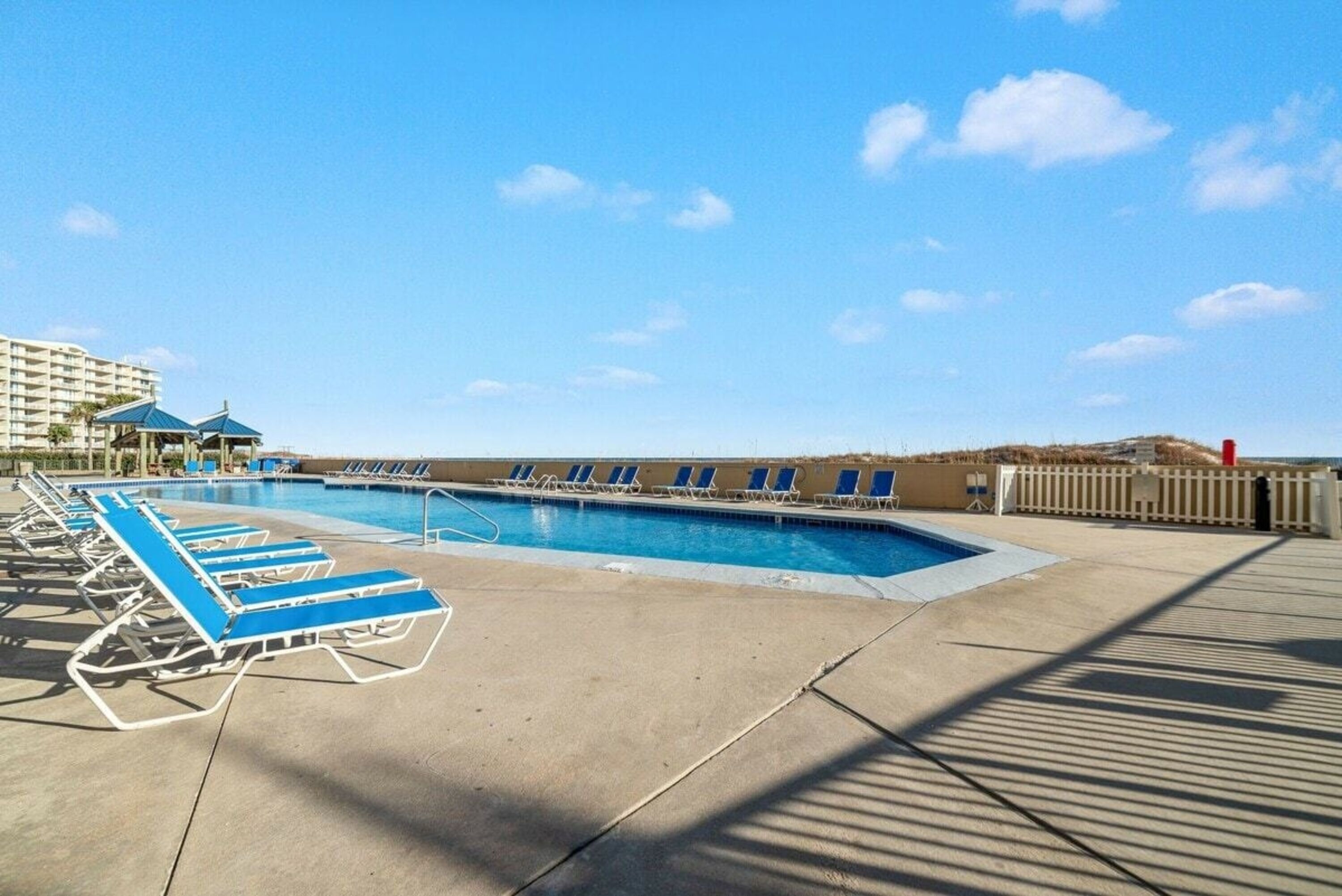Ein Schwimmbecken mit blauen Liegestühlen und blauem Himmel.