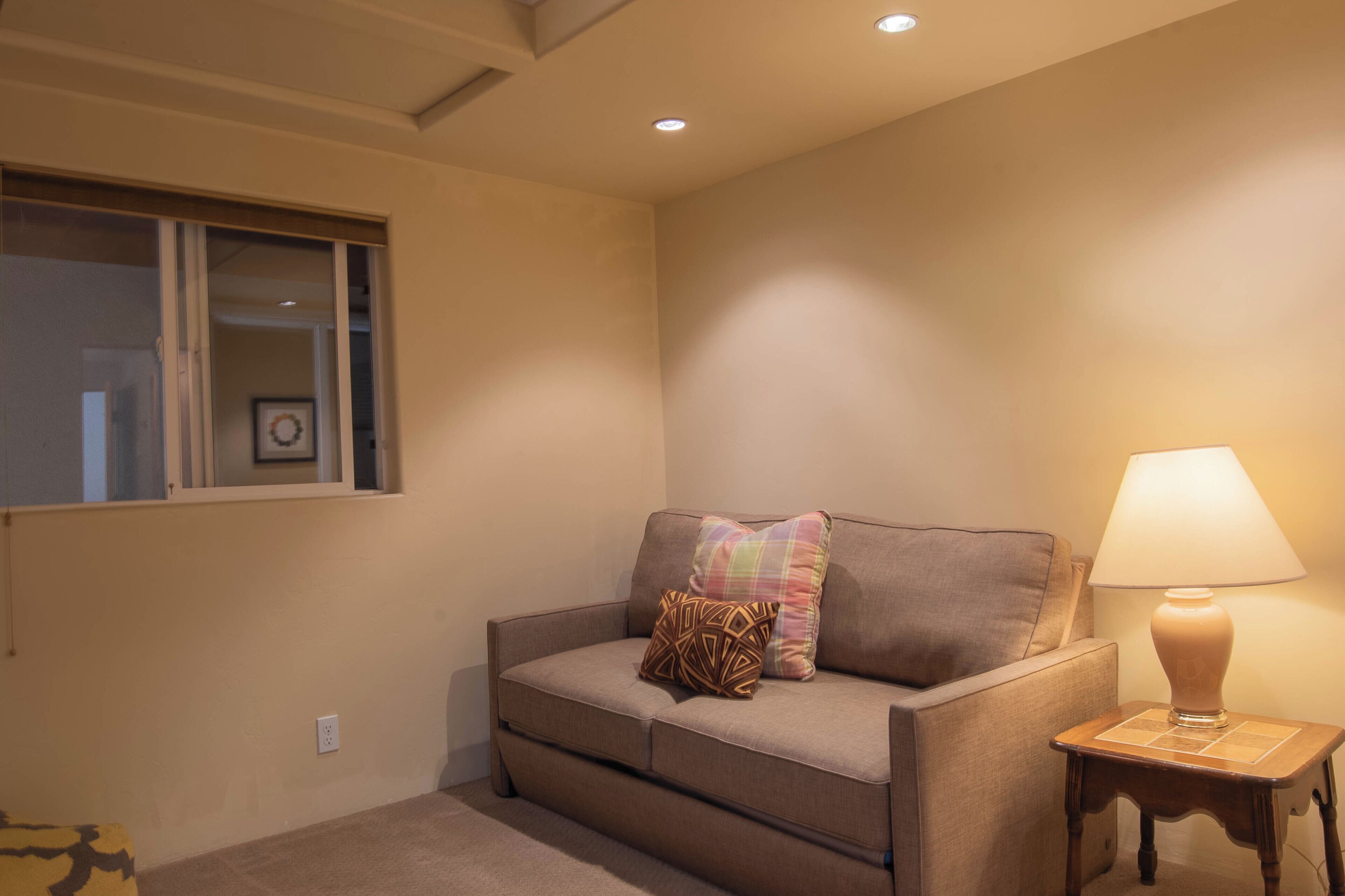 A cozy living room with a sofa, a lamp, and a window.