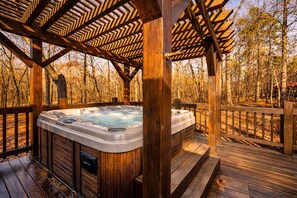Ein Whirlpool unter einer Hollaube mit Wald im Hintergrund.