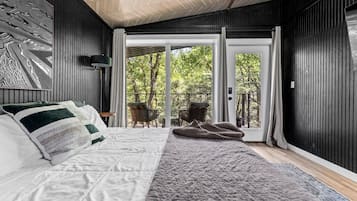 A bedroom with a bed, a large window, and a view of the outdoors.