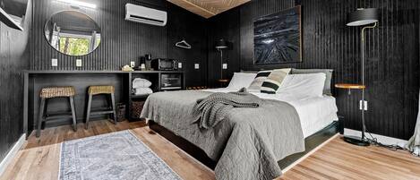 Un dormitorio con cama, mesitas de noche, espejo, lámpara colgante y aire acondicionado instalado en la pared.