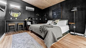 Ein Schlafzimmer mit einem Bett, Nachttischen, einem Spiegel, einer Hängelampe und einer Wandklimaanlage.