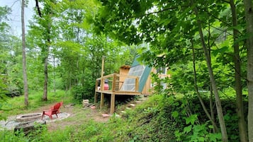 Una cabaña de madera con terraza, rodeada de un bosque denso.