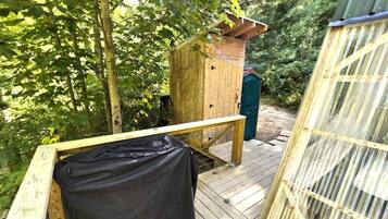 A wooden deck with a bench, a small wooden structure, and a green door.
