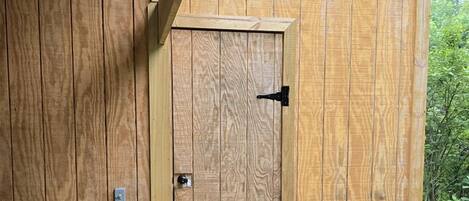 A wooden shed with a door labeled 'GENERATOR' and a smaller door labeled 'SHOWER.'