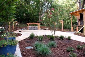 Un jardín ajardinado con un pérgola, un muro de piedra y una terraza de madera.