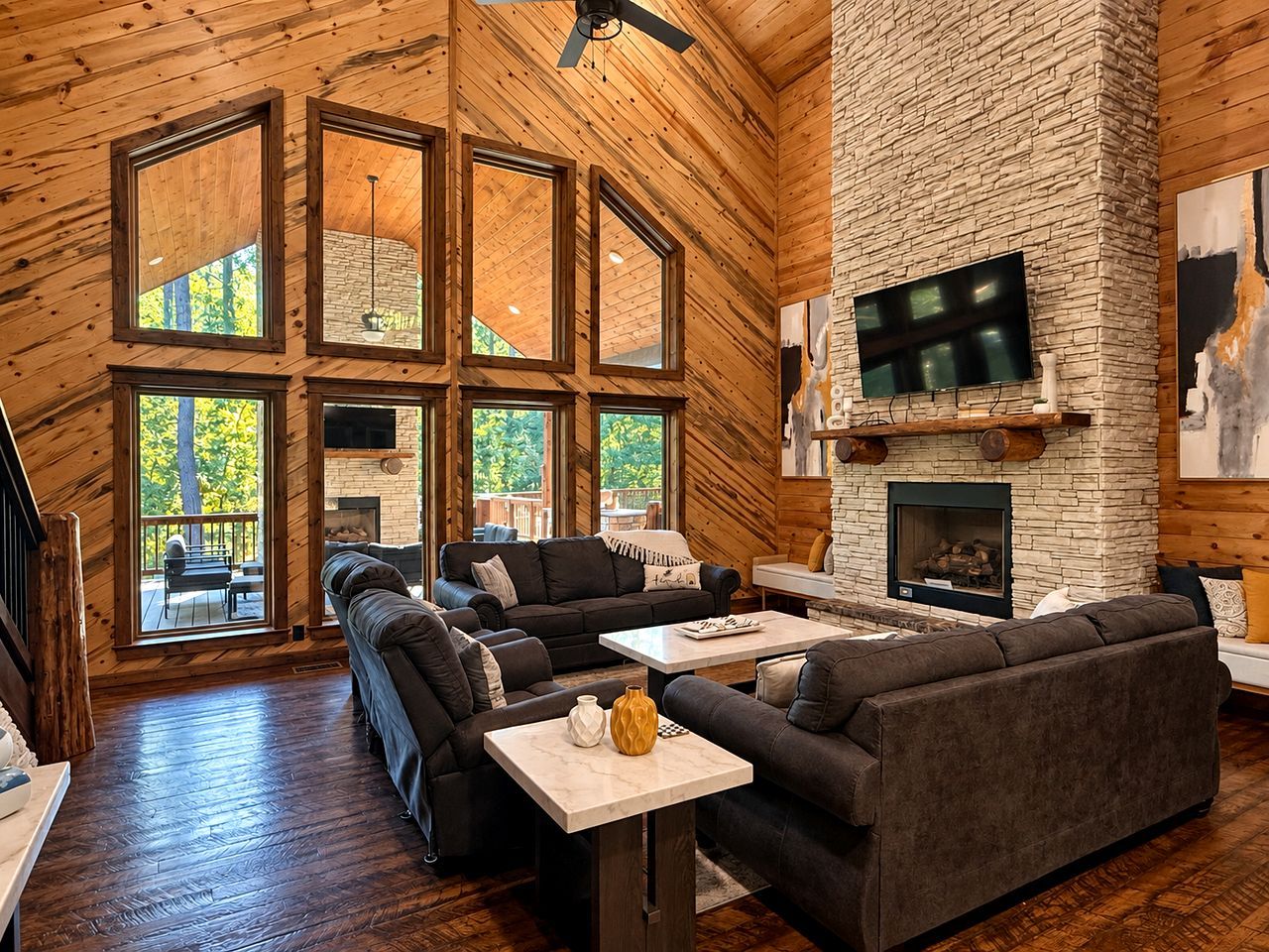 A spacious living room with a fireplace, large windows, and a stone wall.