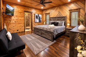 Ein Schlafzimmer mit Bett, Sofa, Fernseher und einer Duschkabine.