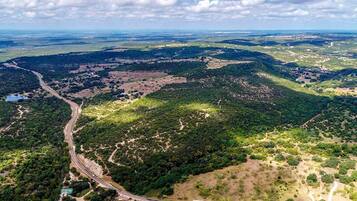 Une vue aérienne d’un paysage avec une route sinueuse, une végétation luxuriante et un petit bâtiment doté d’un toit végétalisé.