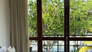 A bedroom with a bed, a ceiling fan, and a view of trees and a deck outside. - Ko Lake -Eagle Nest r5 (Ahangama)