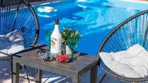 A poolside setting with a table, chairs, a bottle of Malibu rum, a glass, and a bowl of fruit. - Villa Lemily with private pool by Villas Guide (Matulji)