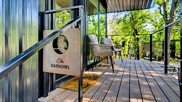 A wooden deck with outdoor seating, a sign reading 'The Barnowl,' and a glass door.