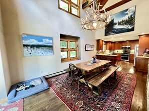 A spacious kitchen with wooden cabinets, a dining area with a bench, and a large rug. - Secluded Cottage with Stunning Sights in Winhall, Vermont (Winhall)