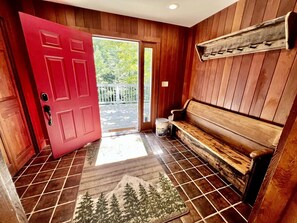 A wooden interior with a red door, a bench, and a tiled floor. - Secluded Cottage with Stunning Sights in Winhall, Vermont (Winhall)
