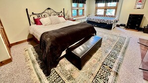 A bedroom with a bed, bench, windows, and a dresser. - Secluded Cottage with Stunning Sights in Winhall, Vermont (Winhall)