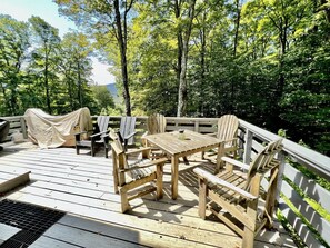 A wooden deck with a table and chairs, surrounded by trees. - Secluded Cottage with Stunning Sights in Winhall, Vermont (Winhall)