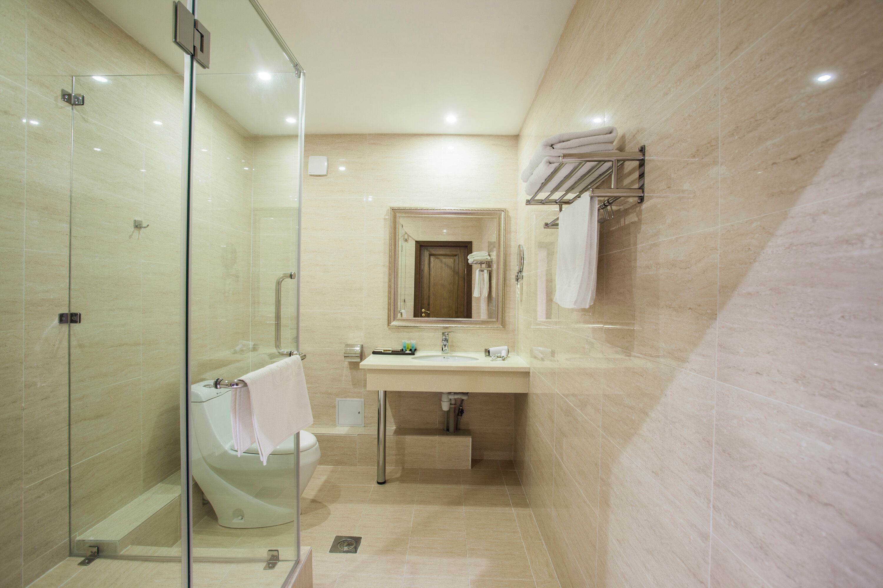 Un bagno moderno con doccia vetrata, lavabo con specchio e porta asciugamani a parete.